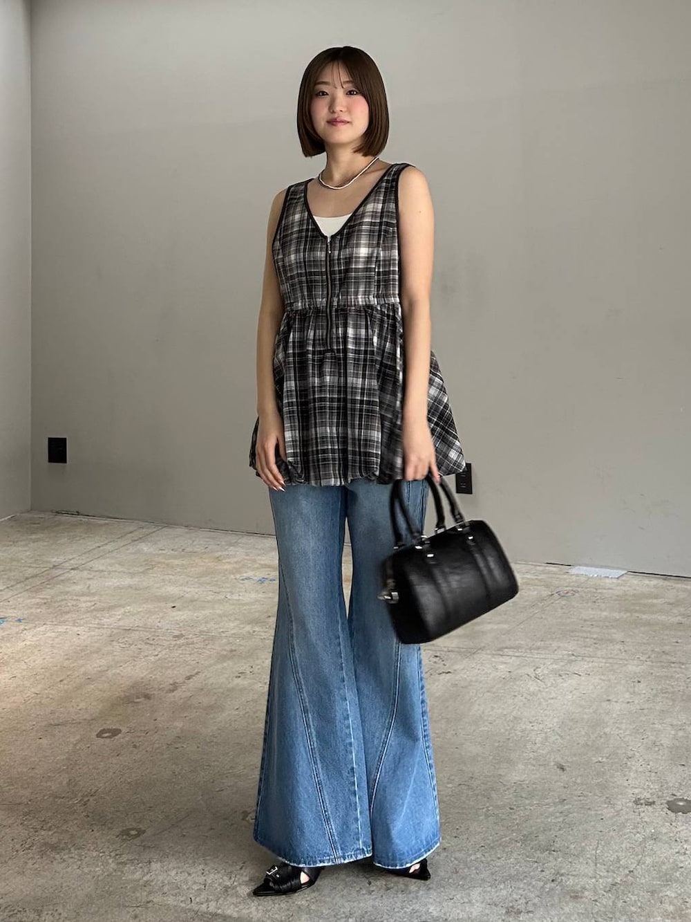 ブルー系のデニムパンツ、ブラック系のボストンバッグ、ブラック系のサンダルを着用したレディースの春コーディネートの7枚目の写真