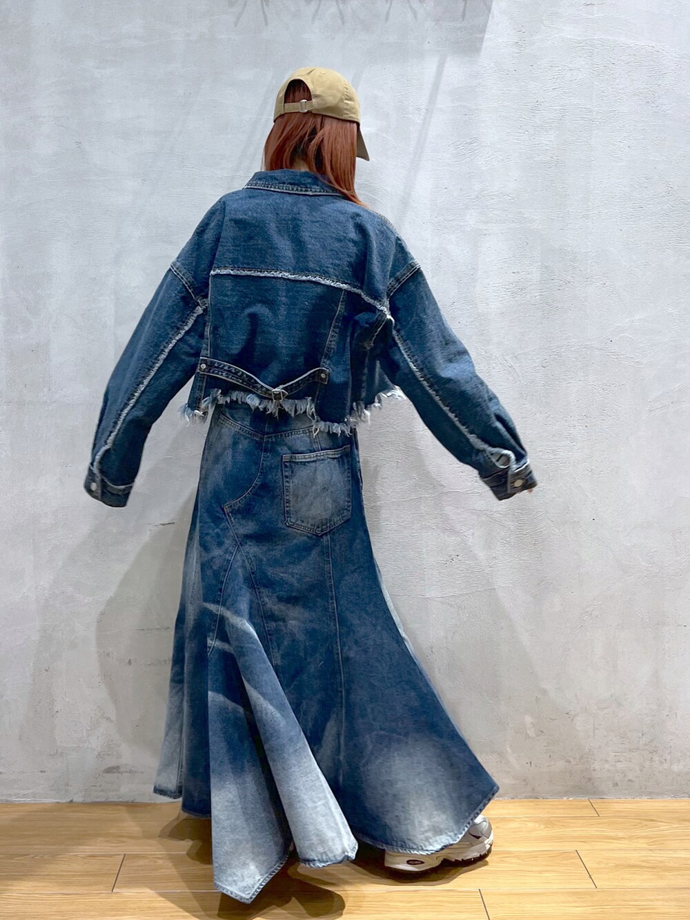 ブルー系のデニムジャケット、ブルー系のデニムスカート、ベージュ系のキャップを着用したレディースの春コーディネートの2枚目の写真