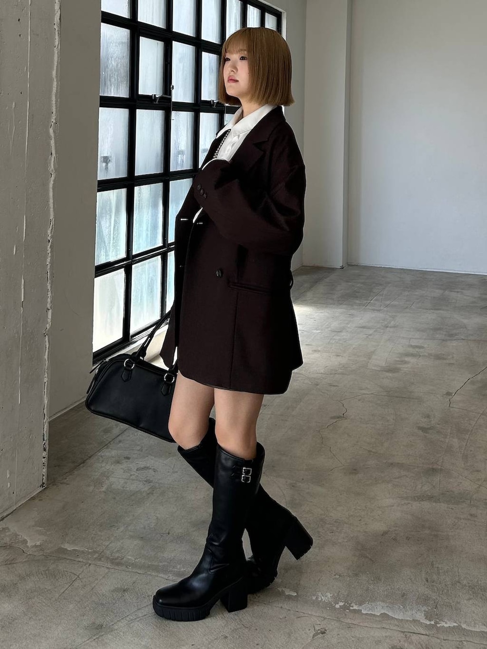 ブラック系のブーツ、ブラック系のボストンバッグ、ホワイト系のシャツ/ブラウスを着用したレディースの秋コーディネートの3枚目の写真