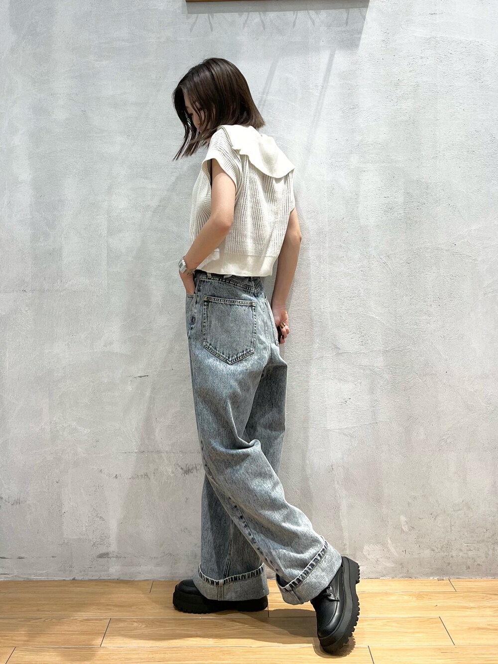 ホワイト系のニット/セーター、ブルー系のデニムパンツ、ブラック系のブーツを着用したレディースの夏コーディネートの3枚目の写真