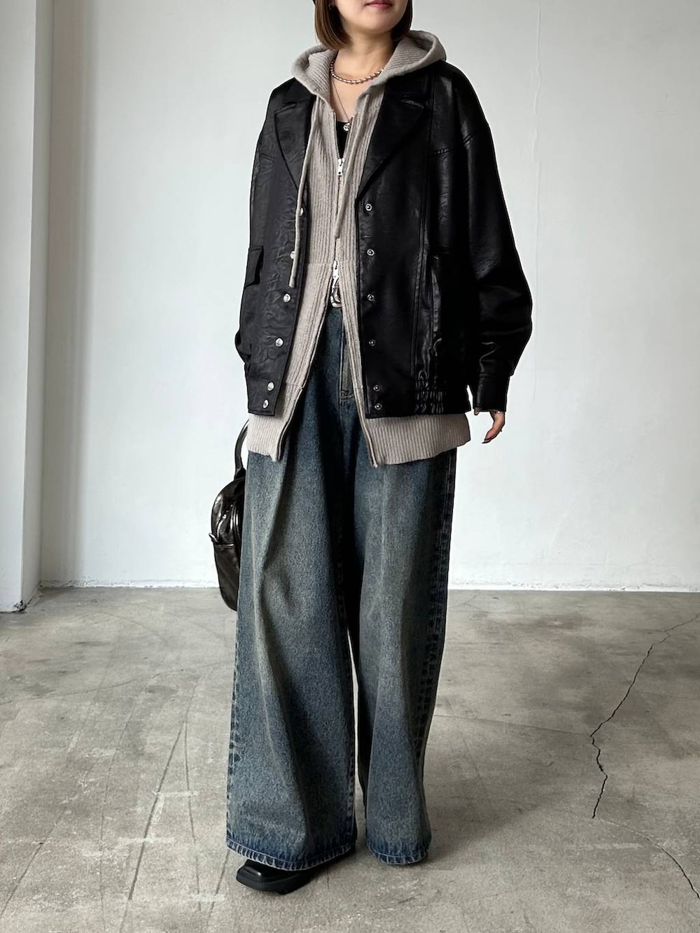 ブルー系のデニムパンツ、ブラック系のブルゾン、ブラック系のブーツを着用したレディースの冬コーディネートの2枚目の写真