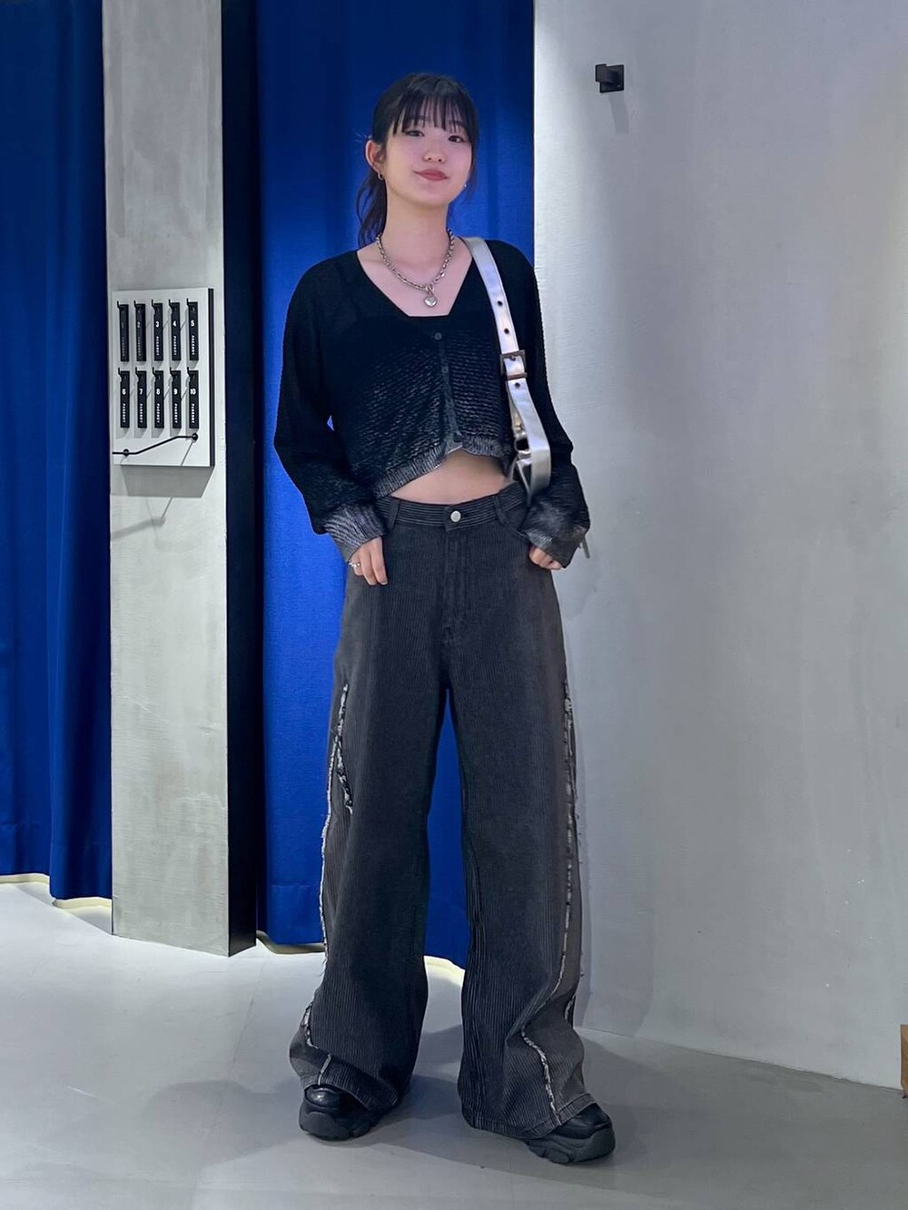 ブラック系のスニーカー、ブラック系のカーディガン/ボレロ、ブラック系のデニムパンツを着用したレディースの秋コーディネートの3枚目の写真