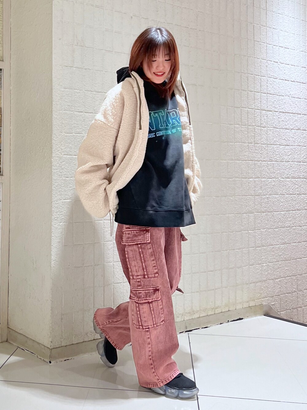 ブラウン系のデニムパンツ、ブラック系のパーカー、ホワイト系のブルゾンを着用したレディースの冬コーディネートの2枚目の写真