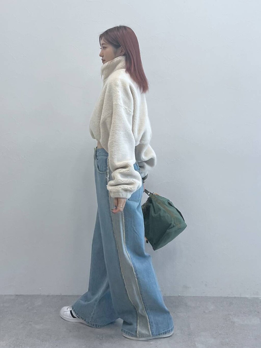 ブルー系のデニムパンツ、グリーン系のショルダーバッグを着用したレディースの秋コーディネートの2枚目の写真