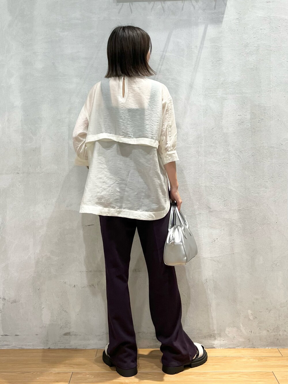 パープル系のスラックス、ホワイト系のシャツ/ブラウス、シルバー系のショルダーバッグを着用したレディースの夏コーディネートの2枚目の写真