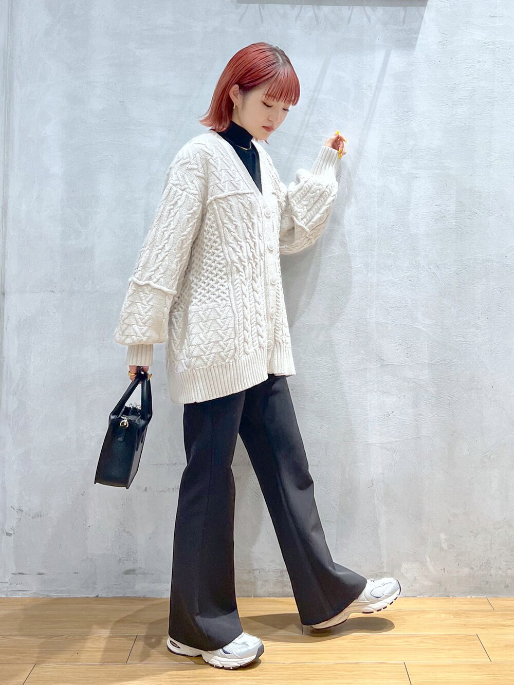 ブラック系のスラックス、ホワイト系のカーディガン/ボレロ、ブラック系のショルダーバッグを着用したレディースの秋コーディネートの2枚目の写真