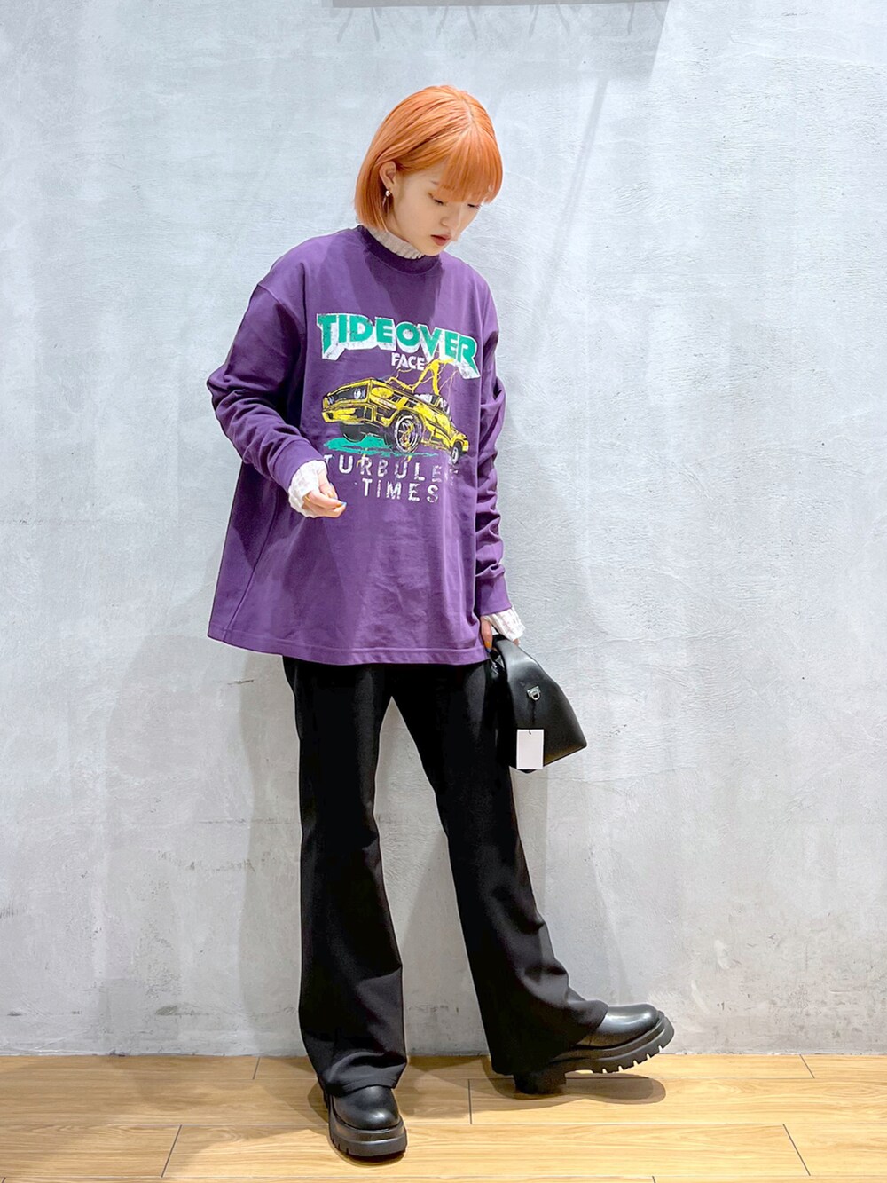 ブラック系のスラックス、ブラック系のショルダーバッグ、パープル系のTシャツ/カットソーを着用したレディースの秋コーディネートの3枚目の写真