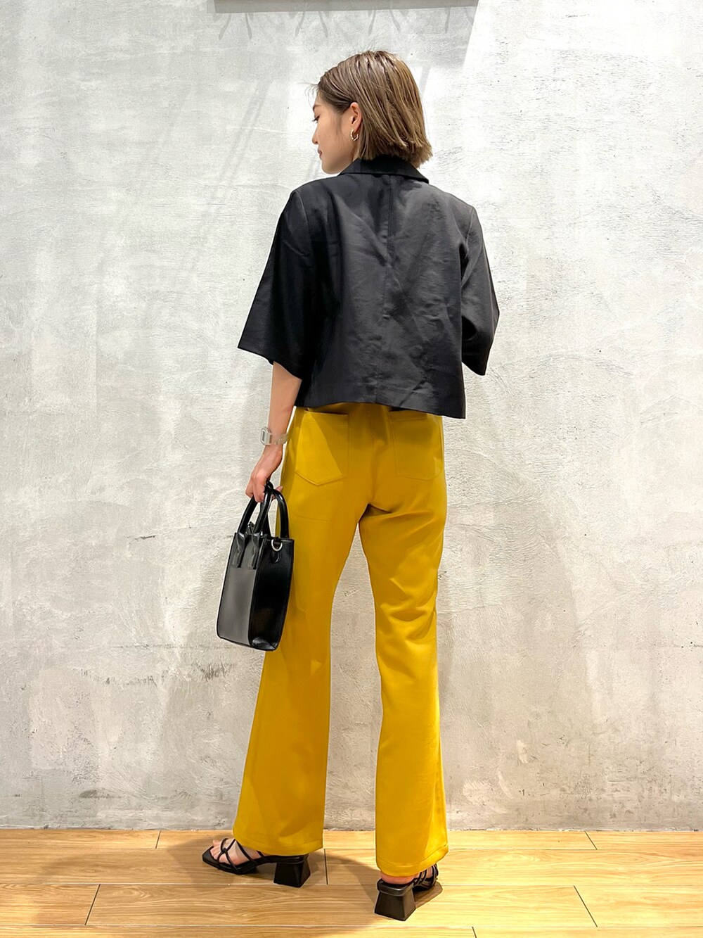 イエロー系のスラックス、ブラック系のサンダル、ブラック系のショルダーバッグを着用したレディースの夏コーディネートの3枚目の写真