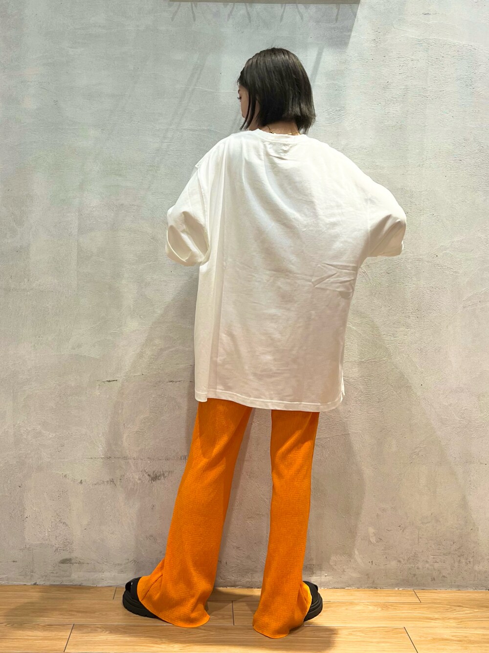 オレンジ系のその他パンツ、ホワイト系のTシャツ/カットソー、ブラック系のサンダルを着用したレディースの夏コーディネートの3枚目の写真