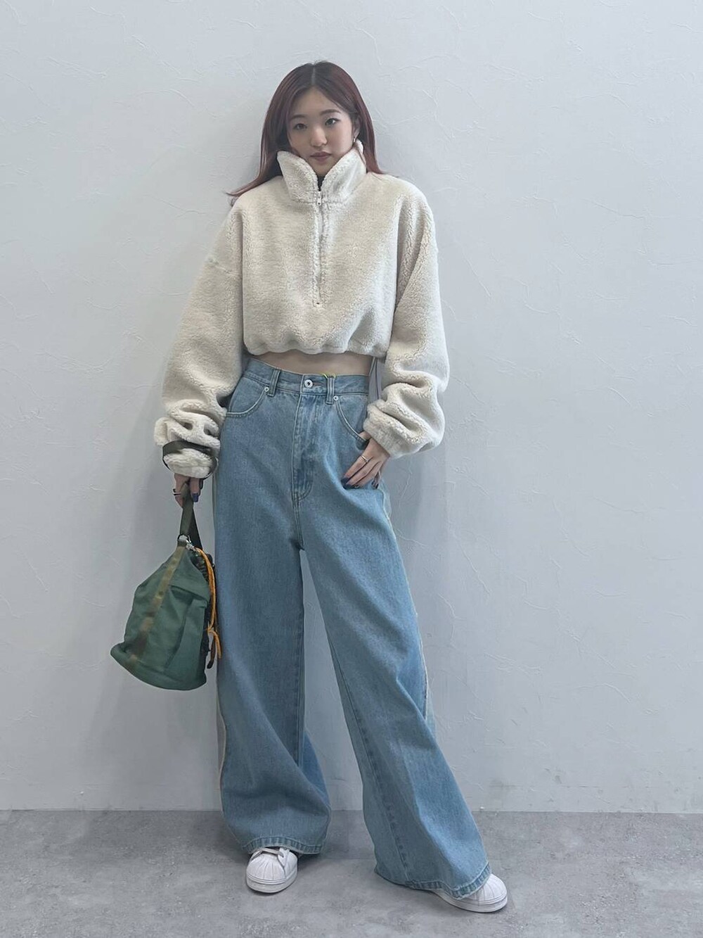 ブルー系のデニムパンツ、グリーン系のショルダーバッグを着用したレディースの秋コーディネートの4枚目の写真