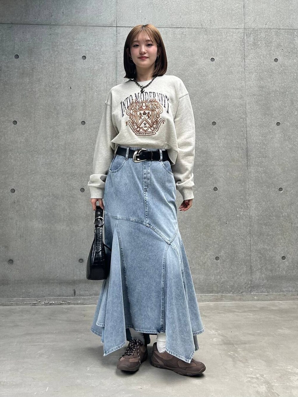 ブラウン系のスニーカー、グレー系のスウェット、ブルー系のデニムスカートを着用したレディースの冬コーディネートの4枚目の写真