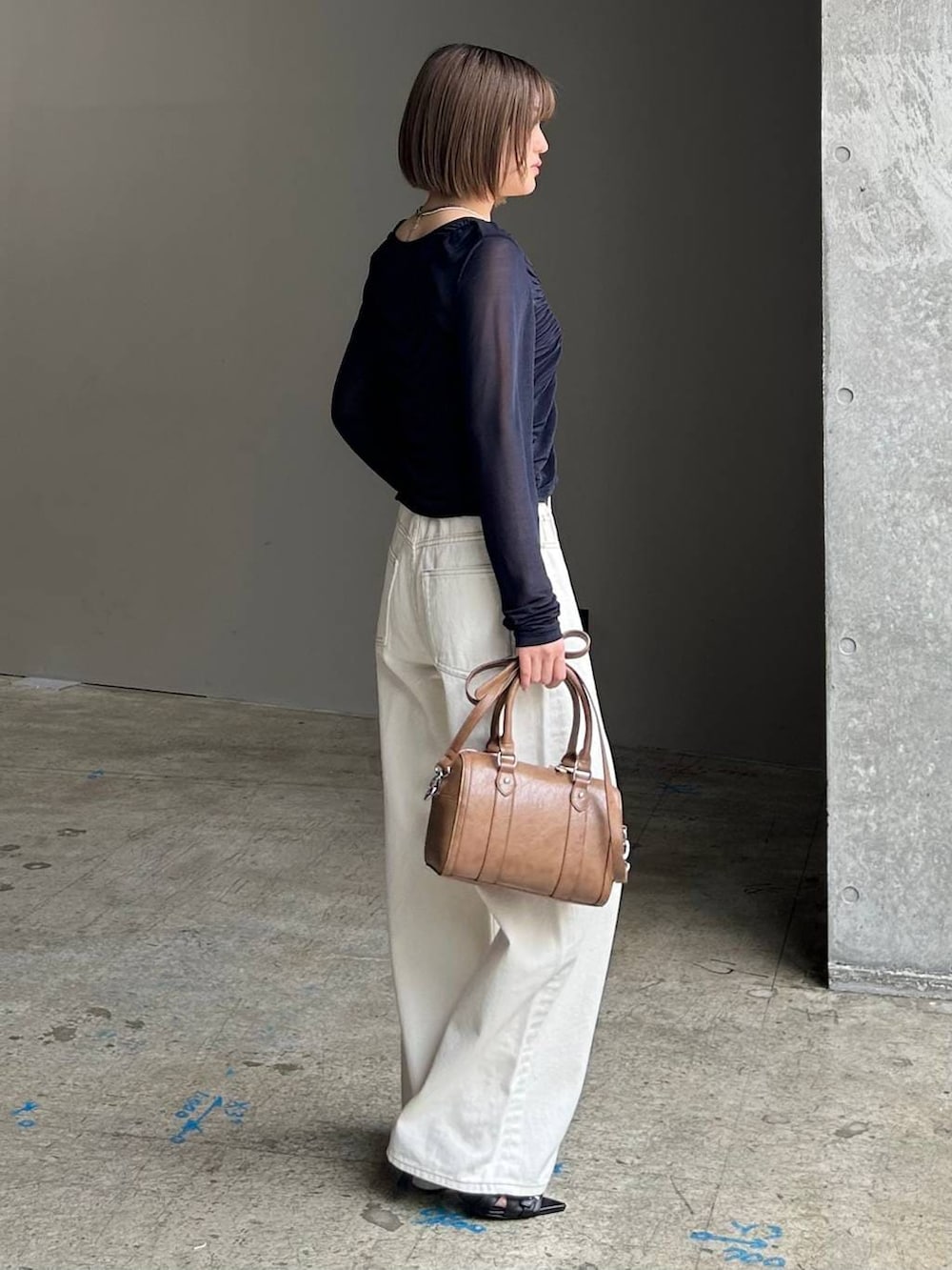 ホワイト系のスラックス、ブラウン系のボストンバッグ、ブラック系のベルトを着用したレディースの春コーディネートの5枚目の写真