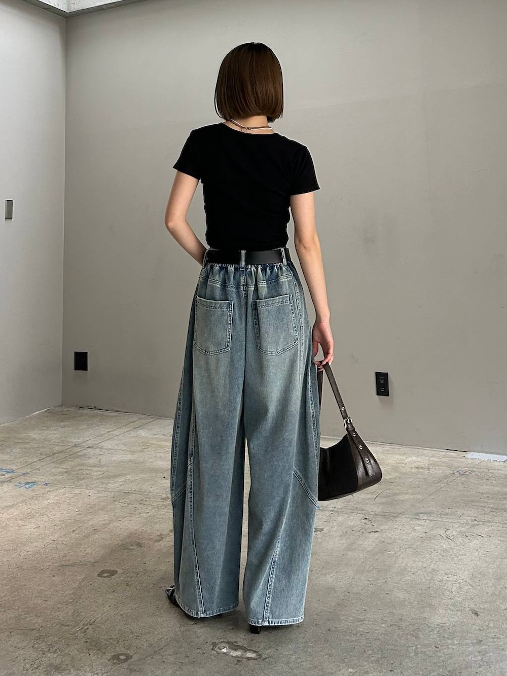 ブラック系のハンドバッグ、ブルー系のデニムパンツ、ブラック系のTシャツ/カットソーを着用したレディースの春コーディネートの4枚目の写真