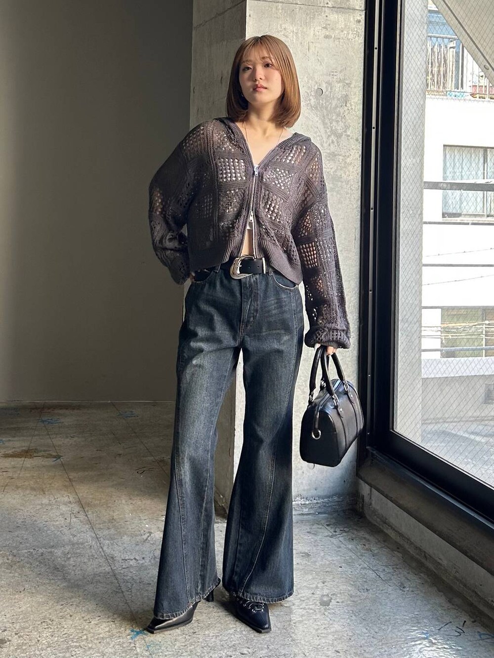 ブルー系のデニムパンツ、ブラック系のボストンバッグ、ブラック系のサンダルを着用したレディースの冬コーディネートの4枚目の写真