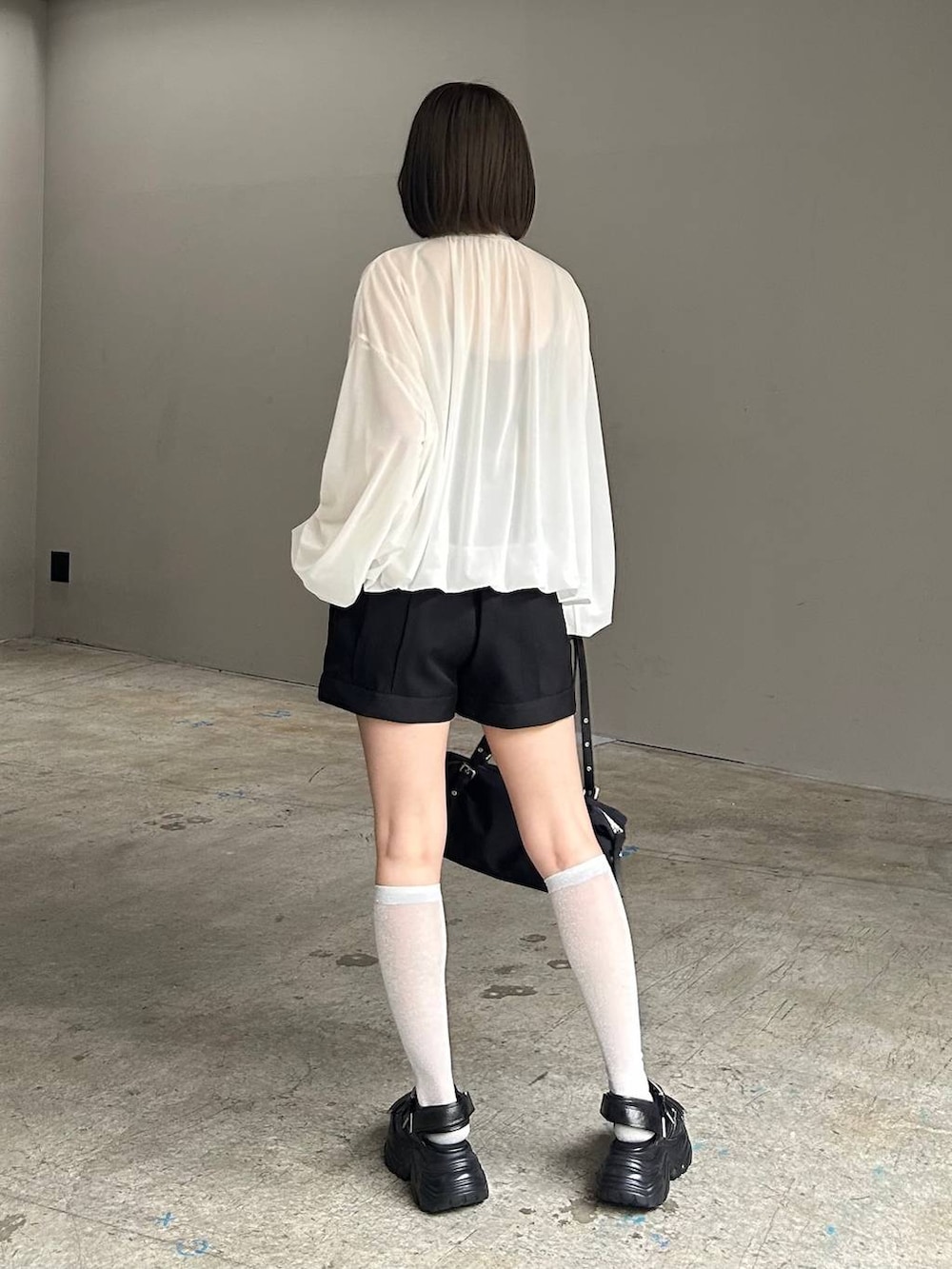 ブラック系のキャミソール、ホワイト系のブルゾン、ブラック系のサンダルを着用したレディースの春コーディネートの5枚目の写真