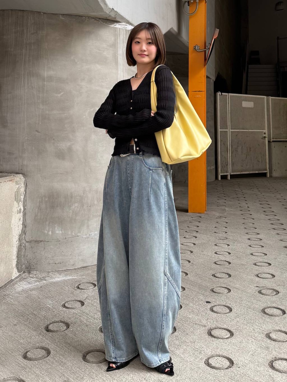 イエロー系のトートバッグ、ブルー系のデニムパンツ、ブラック系のカーディガン/ボレロを着用したレディースの春コーディネートの2枚目の写真