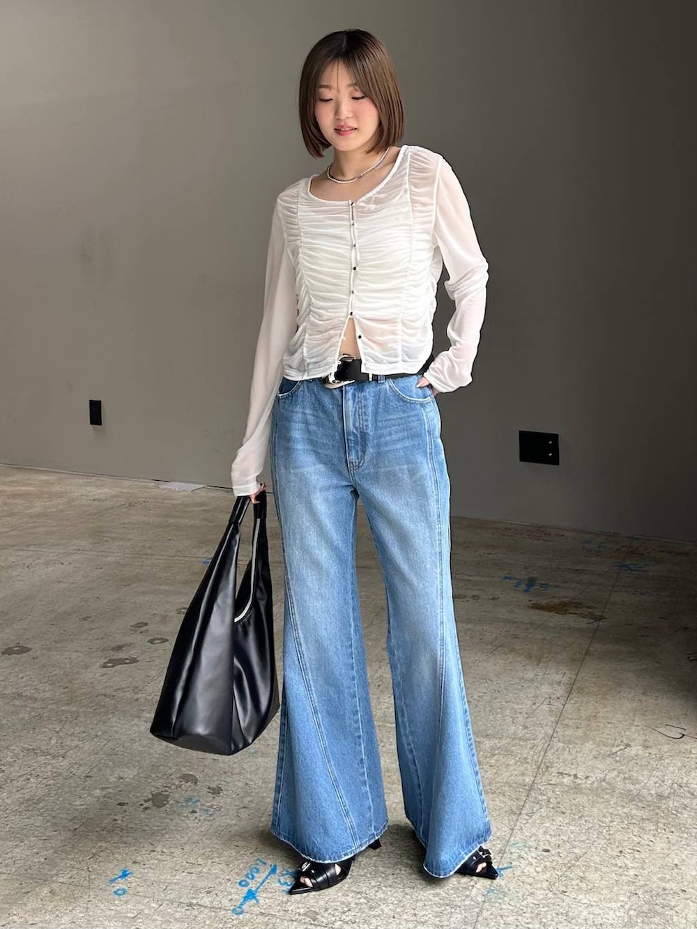 ブルー系のデニムパンツ、ブラック系のトートバッグ、ホワイト系のTシャツ/カットソーを着用したレディースの春コーディネートの5枚目の写真