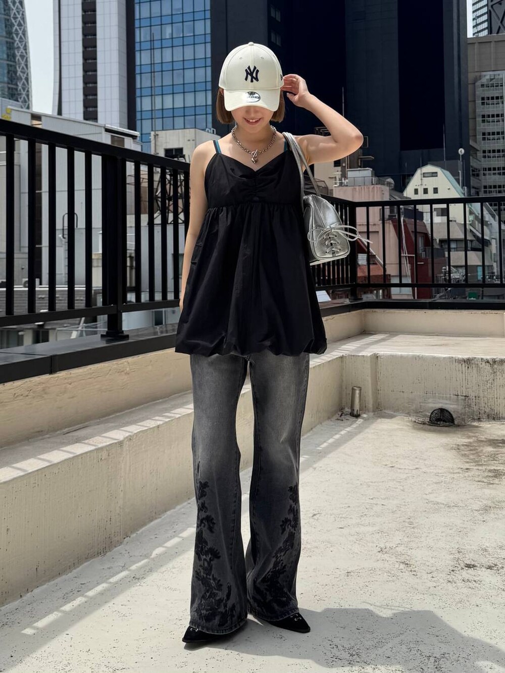 ブラック系のパンプス、ブラック系のデニムパンツ、グリーン系のキャミソールを着用したレディースの夏コーディネートの6枚目の写真