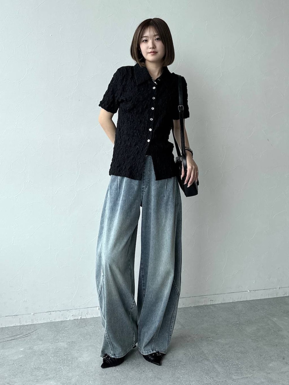 ブルー系のデニムパンツ、ブラック系のショルダーバッグ、ブラック系のサンダルを着用したレディースの春コーディネートの4枚目の写真