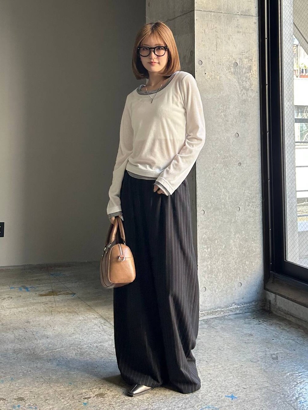 ブラウン系のボストンバッグ、ブラック系のサンダル、ブラック系のスラックスを着用したレディースの冬コーディネートの3枚目の写真