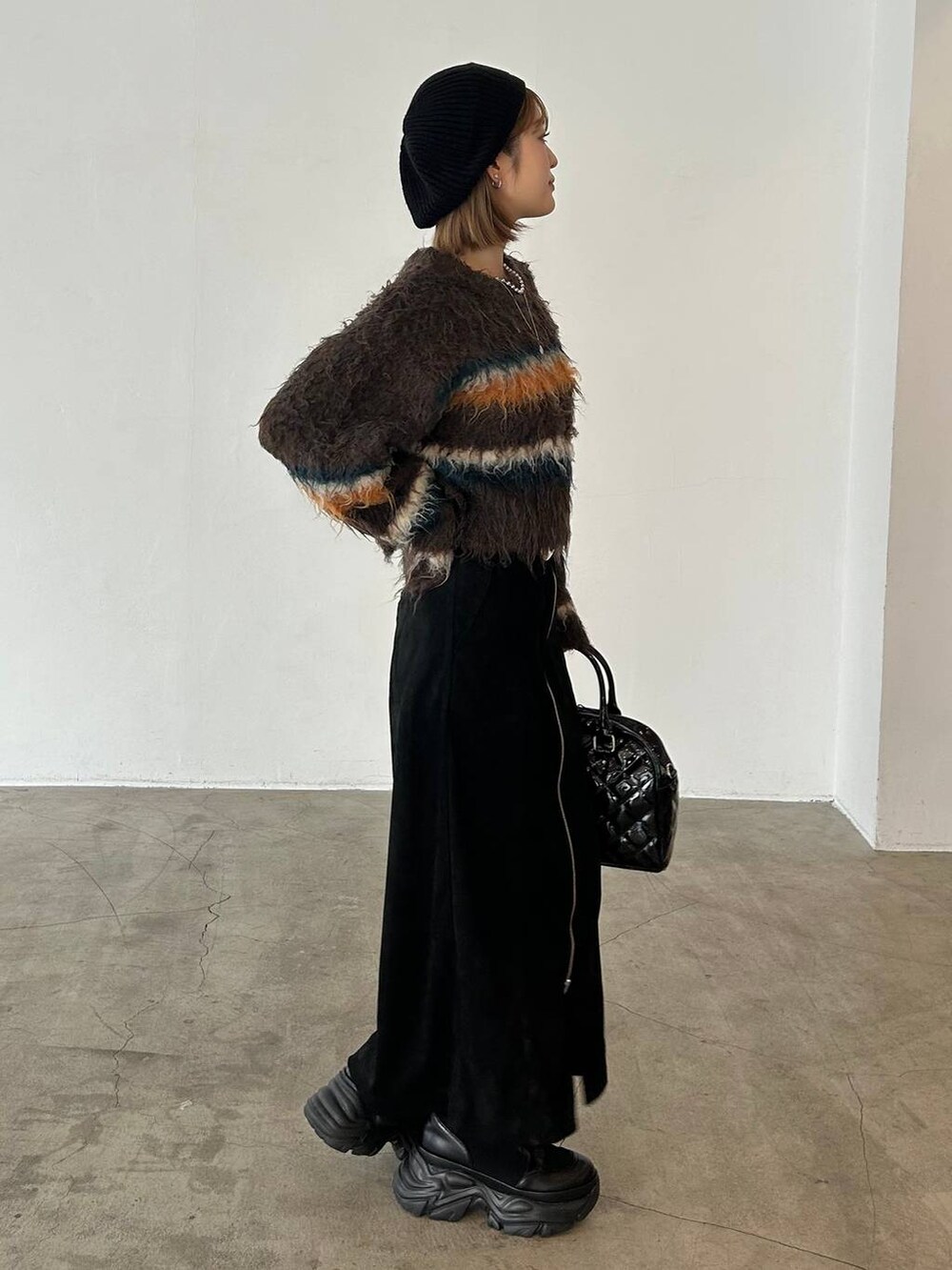 ブラック系のブーツ、ベージュ系のボストンバッグ、ブラウン系のニット/セーターを着用したレディースの冬コーディネートの3枚目の写真