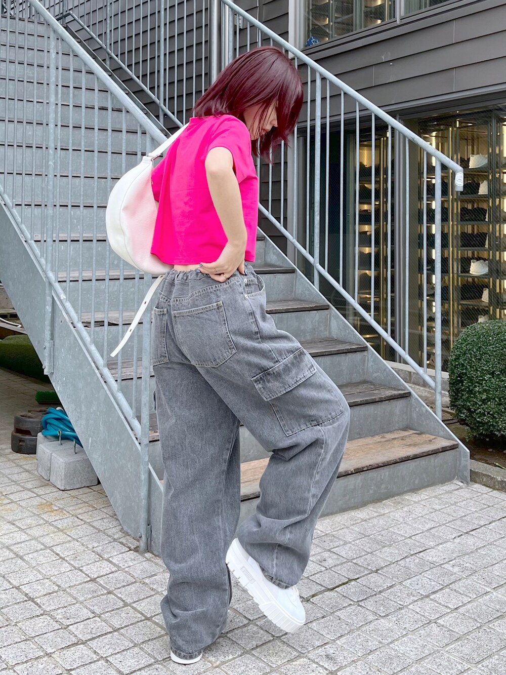 ブラック系のデニムパンツ、ホワイト系のショルダーバッグ、ピンク系のTシャツ/カットソーを着用したレディースの春コーディネートの3枚目の写真