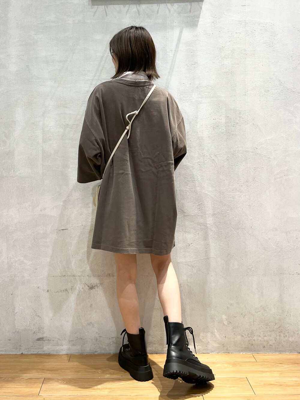 ブラウン系のTシャツ/カットソー、ブラック系のブーツ、ホワイト系のショルダーバッグを着用したレディースの秋コーディネートの4枚目の写真