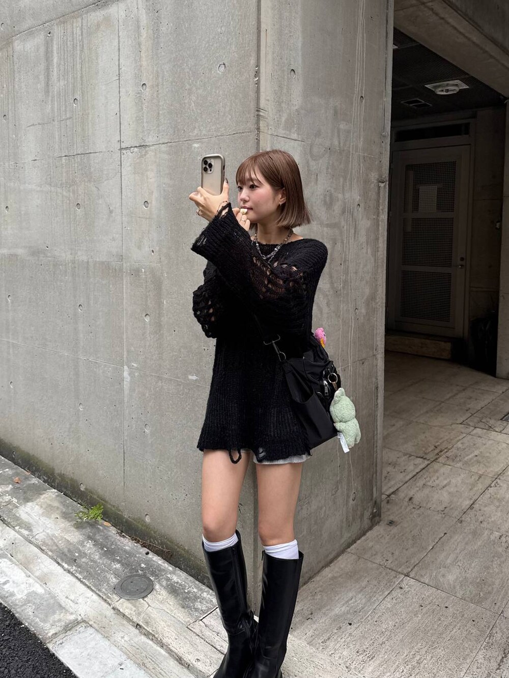 ブラック系のボストンバッグ、ブラック系のニット/セーター、ブラック系のブーツを着用したレディースの秋コーディネートの3枚目の写真