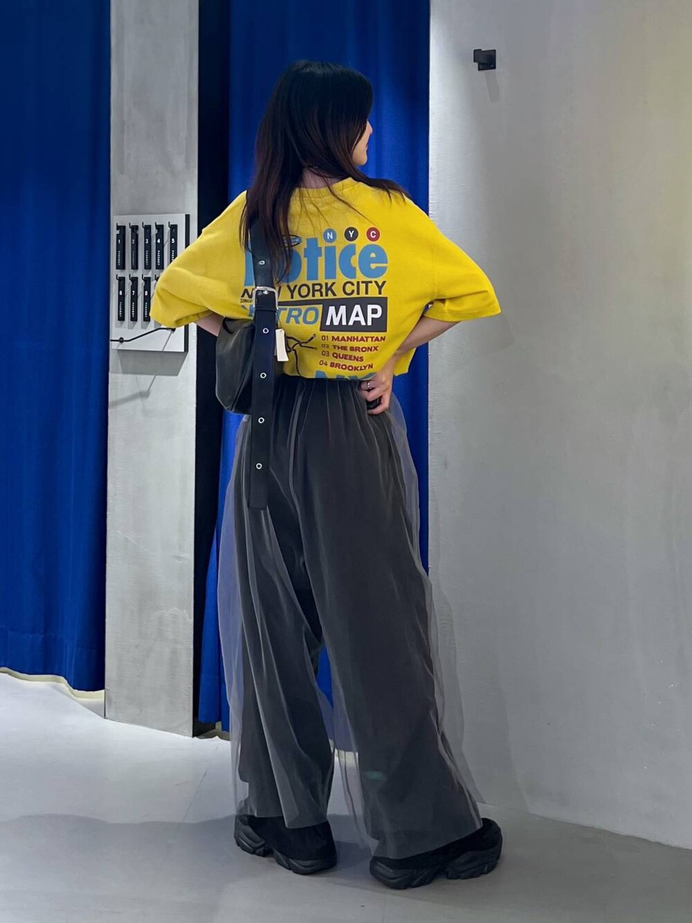 ブラック系のスニーカー、ブラック系のショルダーバッグ、イエロー系のTシャツ/カットソーを着用したレディースの夏コーディネートの3枚目の写真