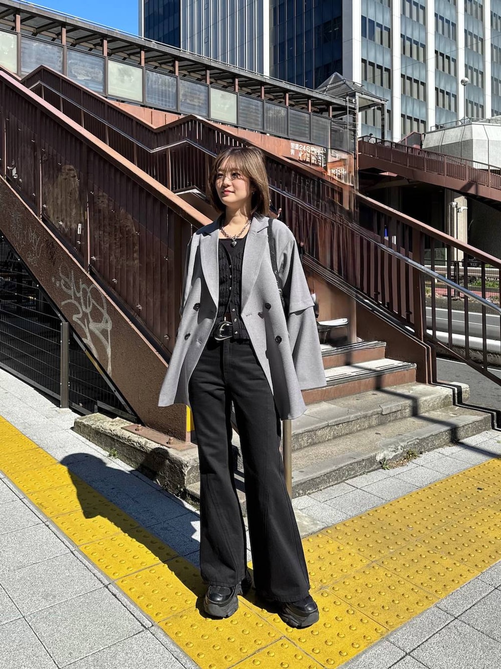 ブラック系のスニーカー、ブラック系のデニムパンツ、ブラック系のハンドバッグを着用したレディースの春コーディネートの5枚目の写真