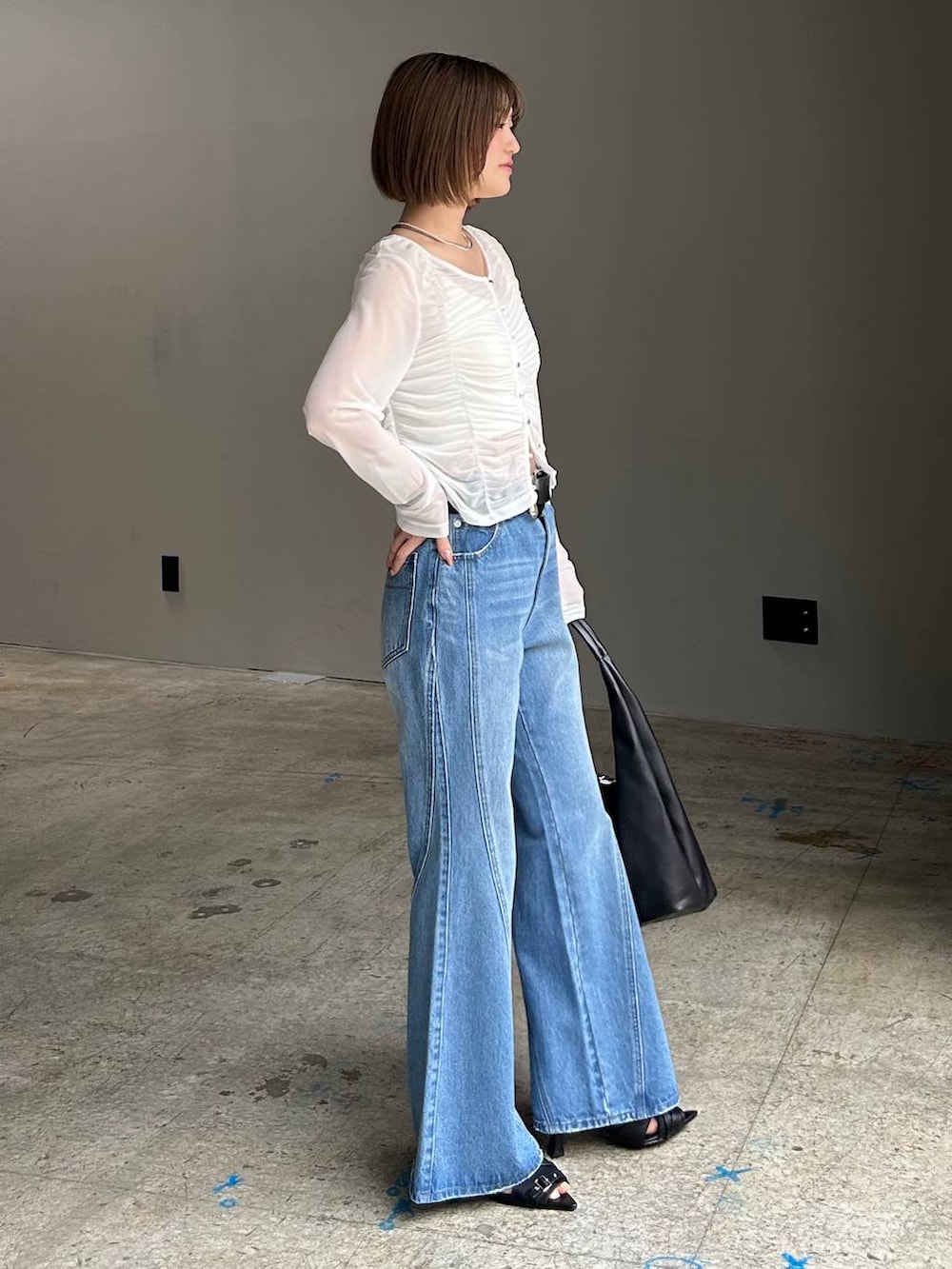 ブルー系のデニムパンツ、ブラック系のトートバッグ、ホワイト系のTシャツ/カットソーを着用したレディースの春コーディネートの2枚目の写真