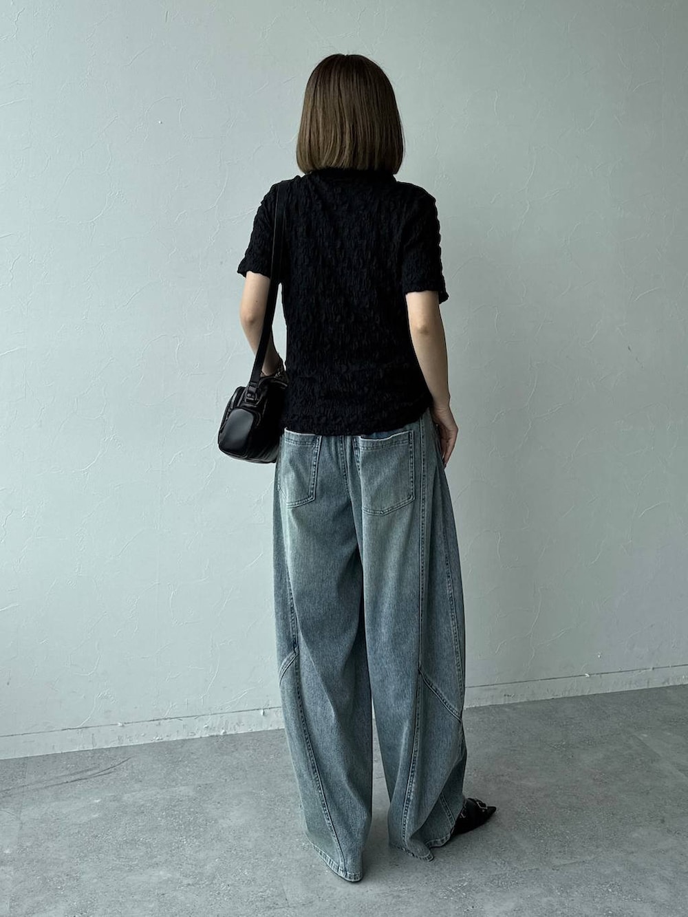 ブルー系のデニムパンツ、ブラック系のショルダーバッグ、ブラック系のサンダルを着用したレディースの春コーディネートの3枚目の写真