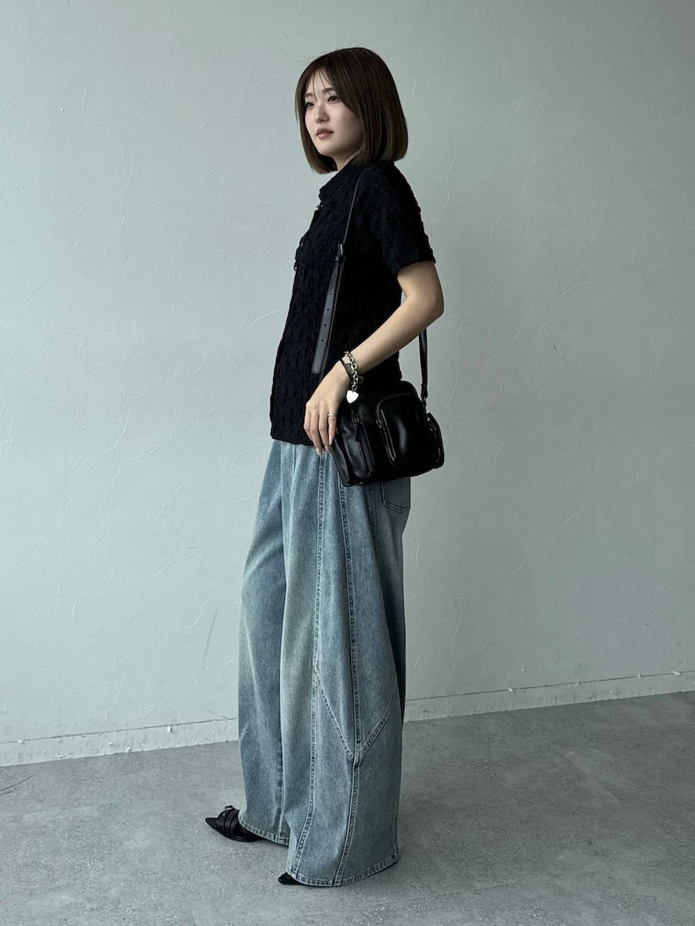 ブルー系のデニムパンツ、ブラック系のショルダーバッグ、ブラック系のサンダルを着用したレディースの春コーディネートの2枚目の写真