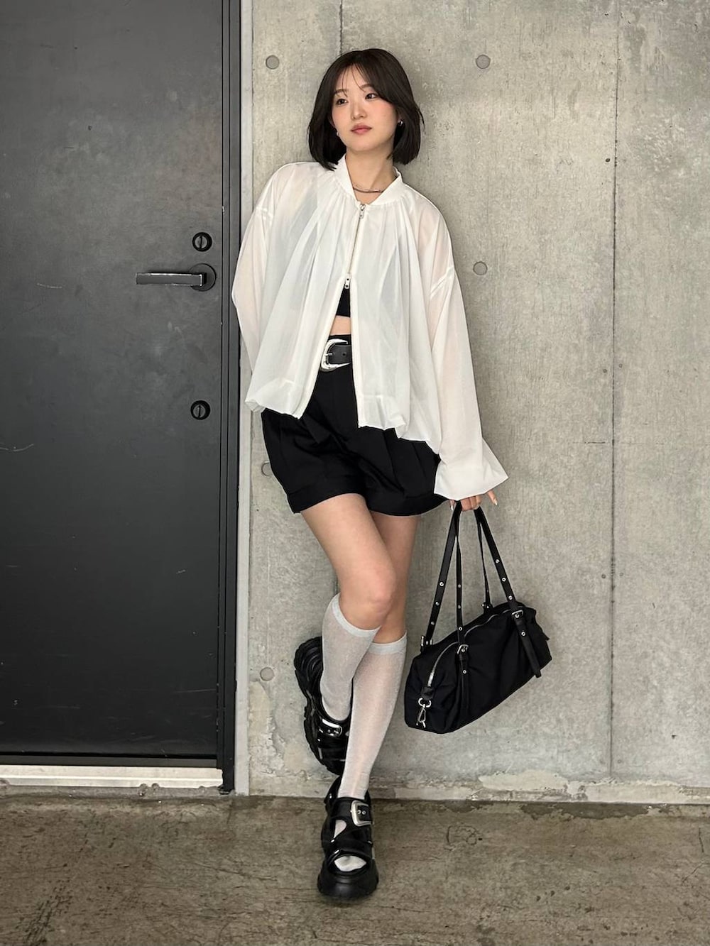 ブラック系のキャミソール、ホワイト系のブルゾン、ブラック系のサンダルを着用したレディースの春コーディネートの6枚目の写真