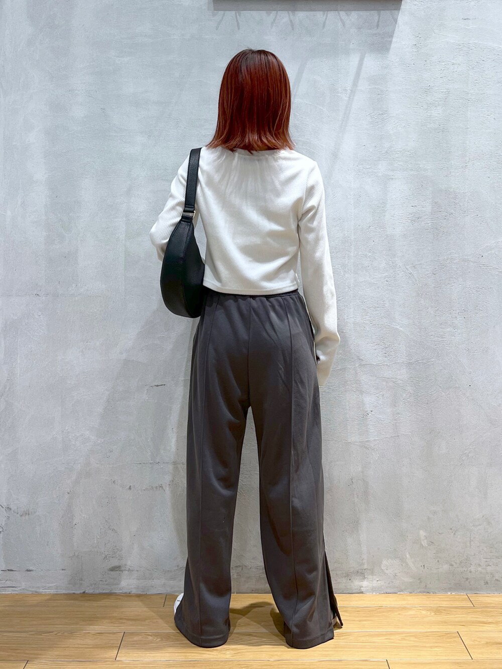 グレー系のスウェットパンツ、ホワイト系のTシャツ/カットソー、ブラック系のショルダーバッグを着用したレディースの冬コーディネートの2枚目の写真