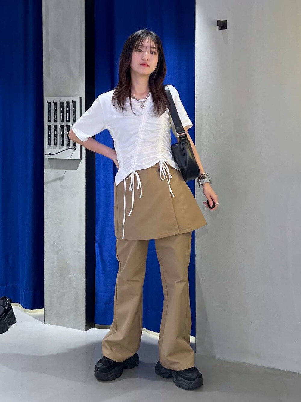 ブラック系のスニーカー、ブラック系のショルダーバッグ、ホワイト系のTシャツ/カットソーを着用したレディースの春コーディネートの2枚目の写真