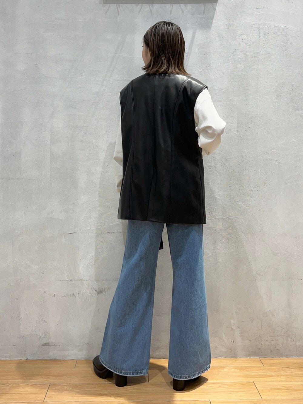 ブルー系のデニムパンツ、ブラック系のブーツ、ブラック系のその他アウターを着用したレディースの秋コーディネートの3枚目の写真