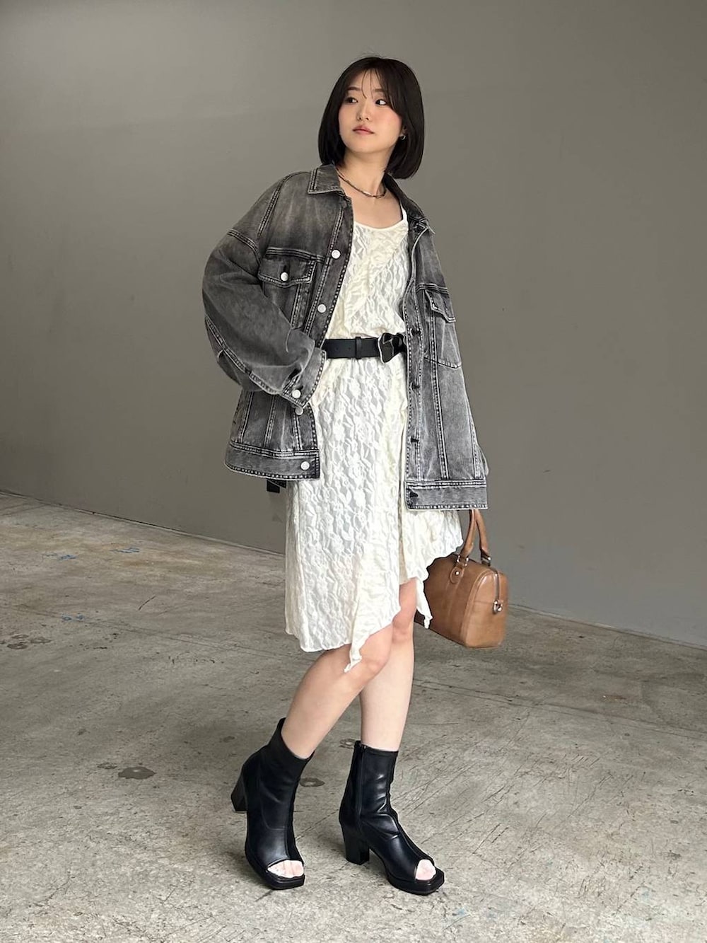 ブラウン系のボストンバッグ、ブラック系のブルゾン、ホワイト系のチュニックを着用したレディースの春コーディネートの2枚目の写真