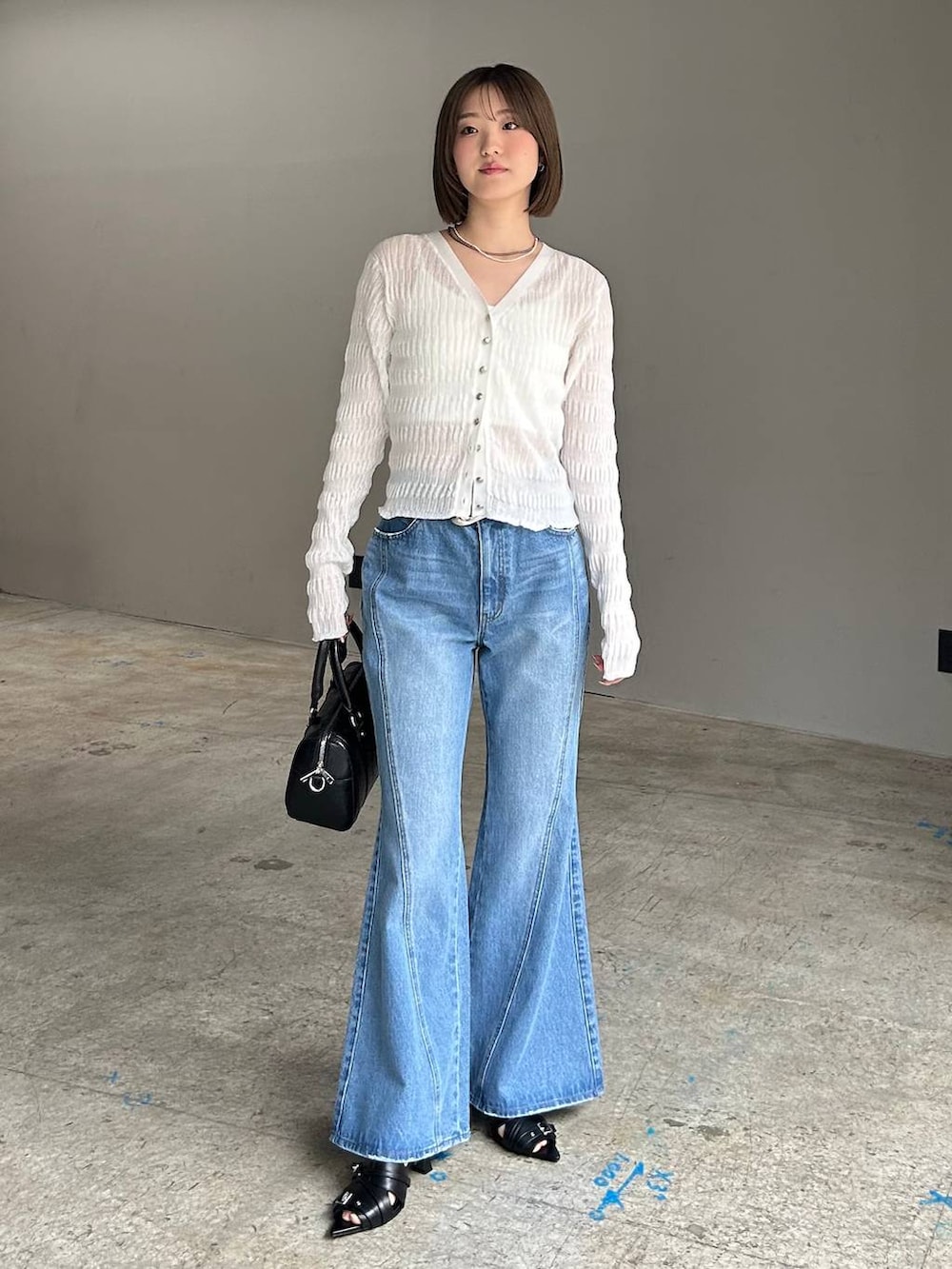 ホワイト系のキャミソール、ブルー系のデニムパンツ、ブラック系のボストンバッグを着用したレディースの春コーディネートの5枚目の写真