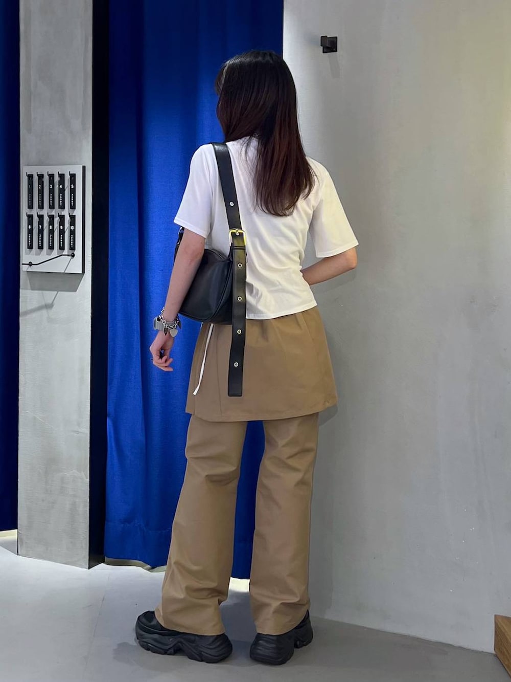 ブラック系のスニーカー、ブラック系のショルダーバッグ、ホワイト系のTシャツ/カットソーを着用したレディースの春コーディネートの4枚目の写真