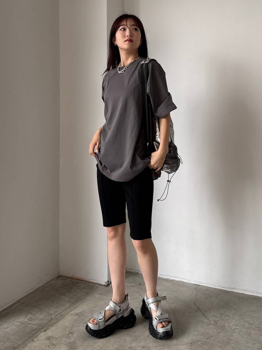 グレー系のサンダル、シルバー系のバックパック/リュック、グレー系のTシャツ/カットソーを着用したレディースの春コーディネートの2枚目の写真