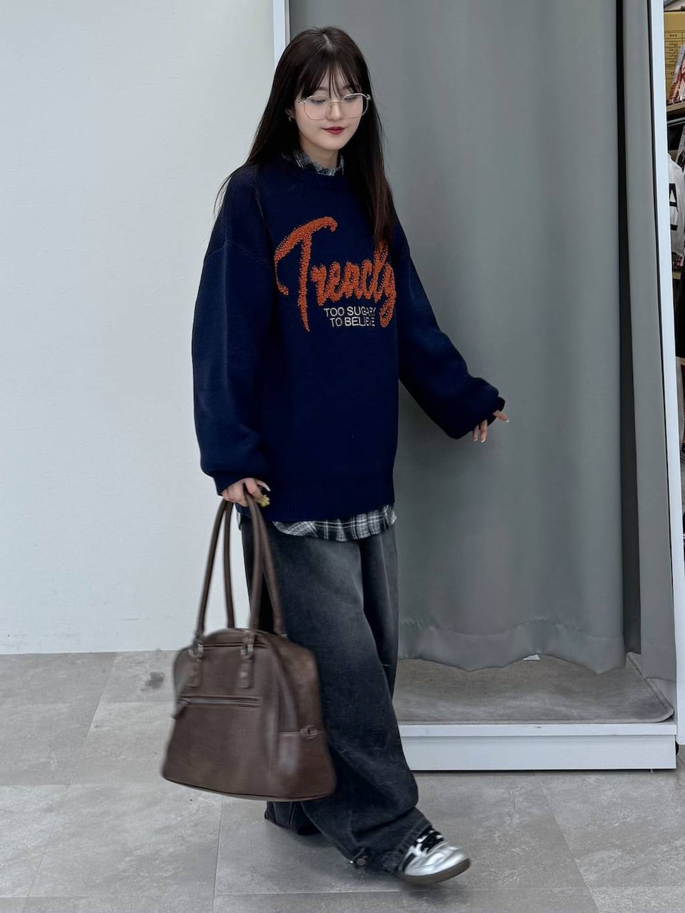 ブルー系のニット/セーター、ブラウン系のボストンバッグ、ブラック系のデニムパンツを着用したレディースの冬コーディネートの3枚目の写真