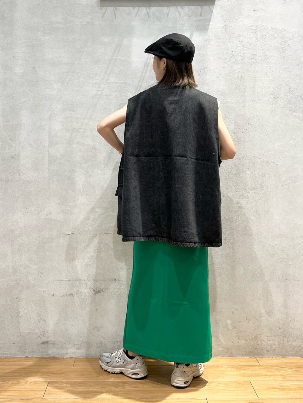 ブラック系のベスト、グリーン系のスカート、グレー系のスニーカーを着用したレディースの夏コーディネートの4枚目の写真