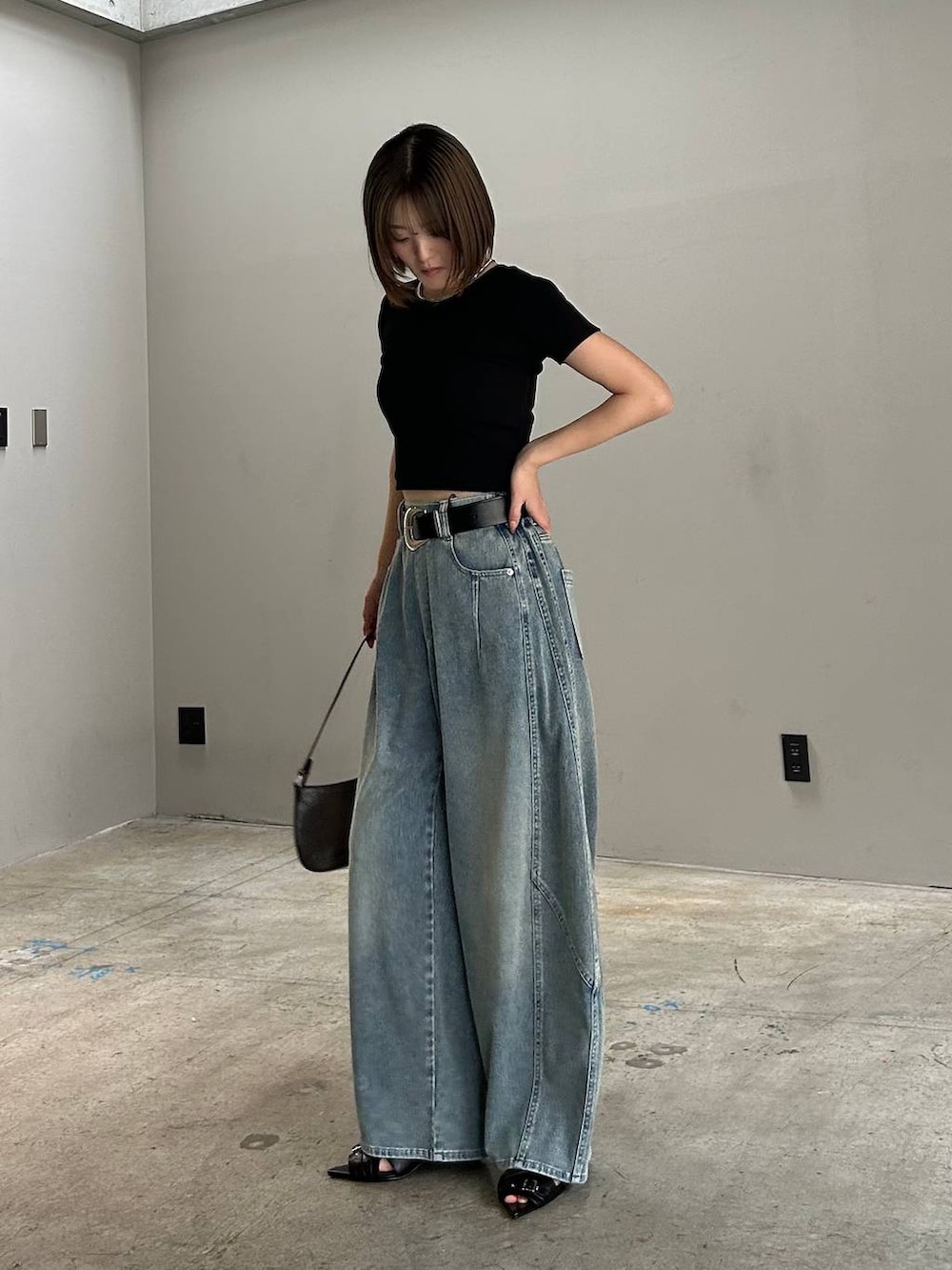 ブラック系のハンドバッグ、ブルー系のデニムパンツ、ブラック系のTシャツ/カットソーを着用したレディースの春コーディネートの2枚目の写真