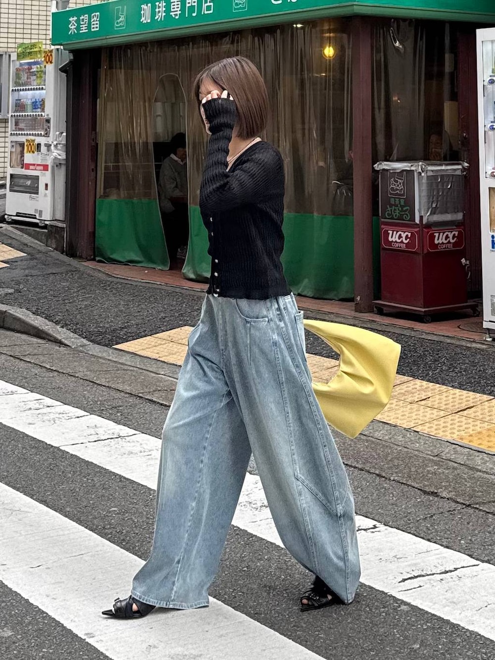 イエロー系のトートバッグ、ブルー系のデニムパンツ、ブラック系のカーディガン/ボレロを着用したレディースの春コーディネートの6枚目の写真