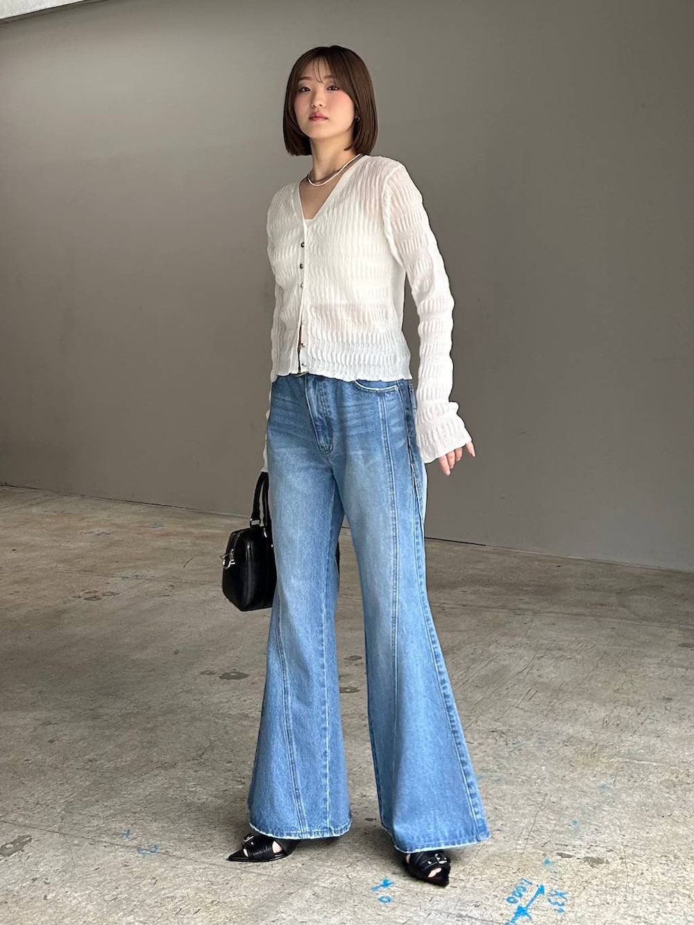 ホワイト系のキャミソール、ブルー系のデニムパンツ、ブラック系のボストンバッグを着用したレディースの春コーディネートの3枚目の写真