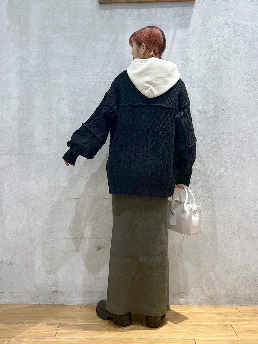 ホワイト系のパーカー、ブラック系のカーディガン/ボレロ、グリーン系のスカートを着用したレディースの秋コーディネートの3枚目の写真