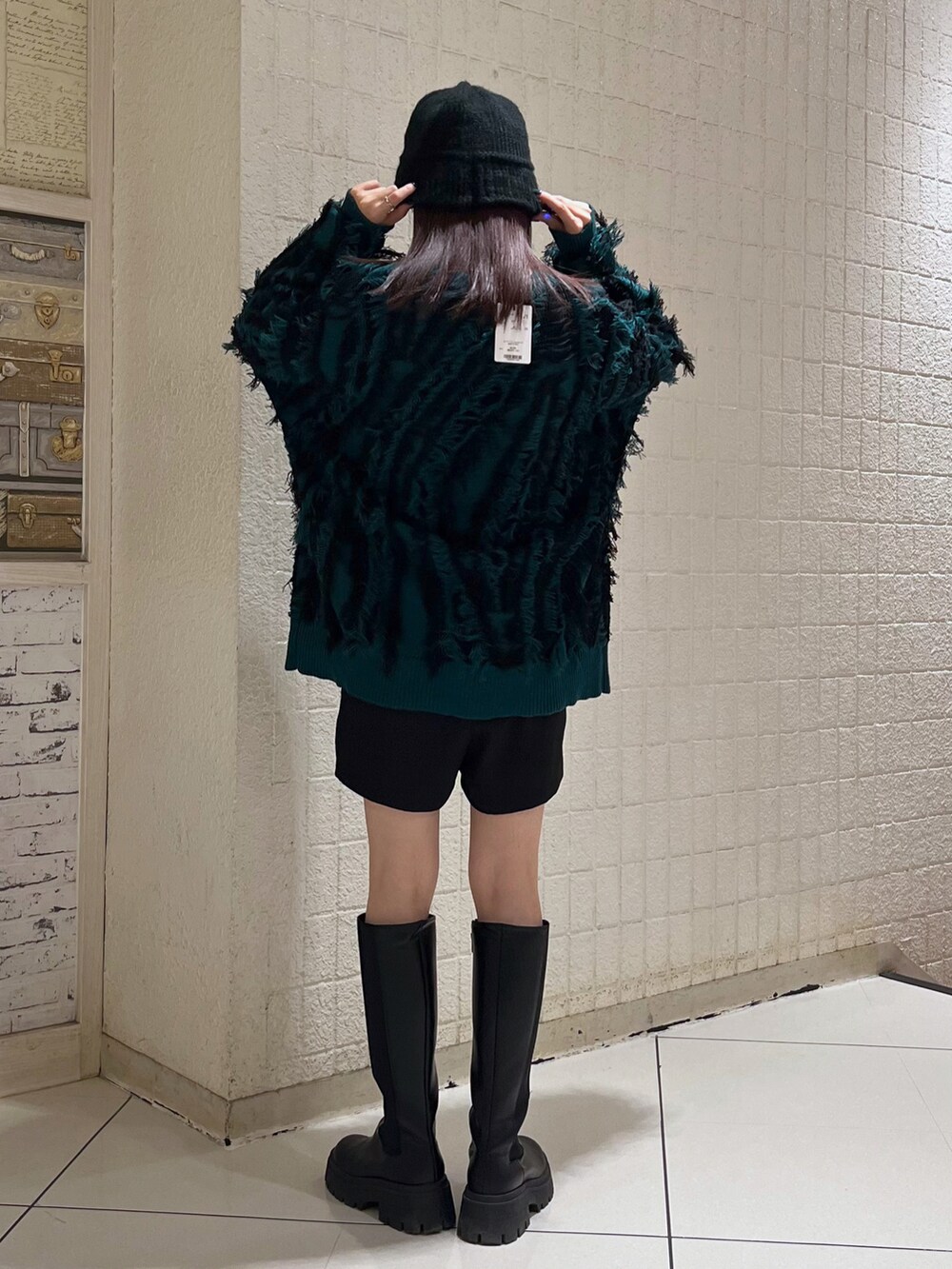 ブラック系のブーツ、ブラック系のその他パンツ、グリーン系のニット/セーターを着用したレディースの冬コーディネートの2枚目の写真