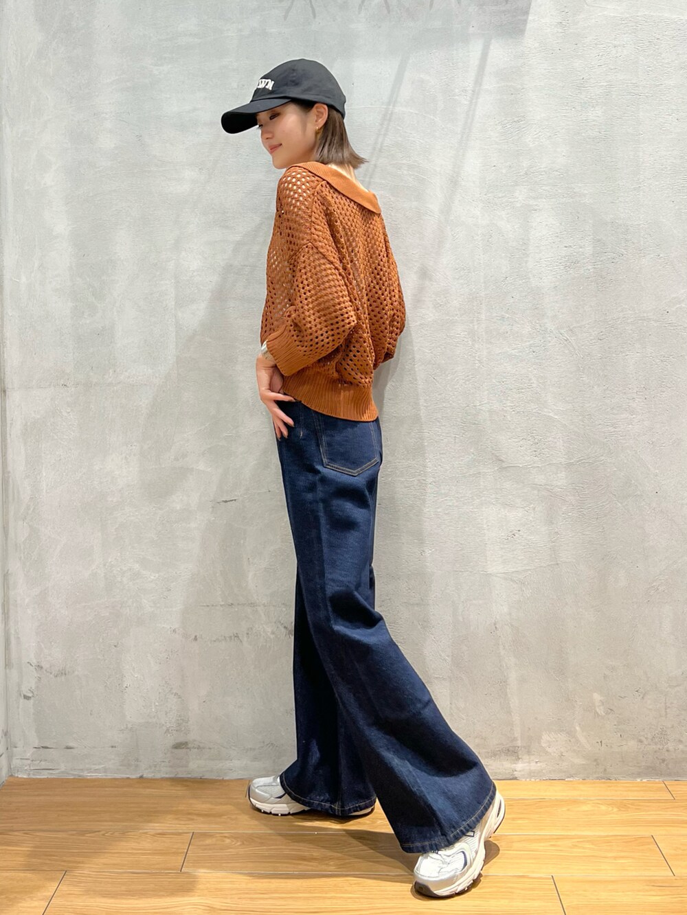 ブルー系のデニムパンツ、ブラウン系のニット/セーター、ホワイト系のキャミソールを着用したレディースの夏コーディネートの2枚目の写真