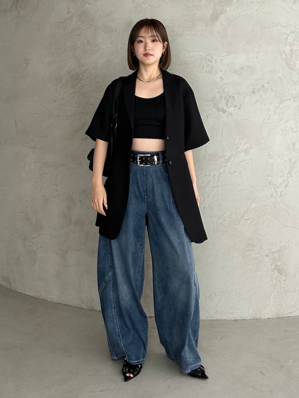 ブラック系のキャミソール、ブルー系のデニムパンツ、ブラック系のサンダルを着用したレディースの春コーディネートの2枚目の写真